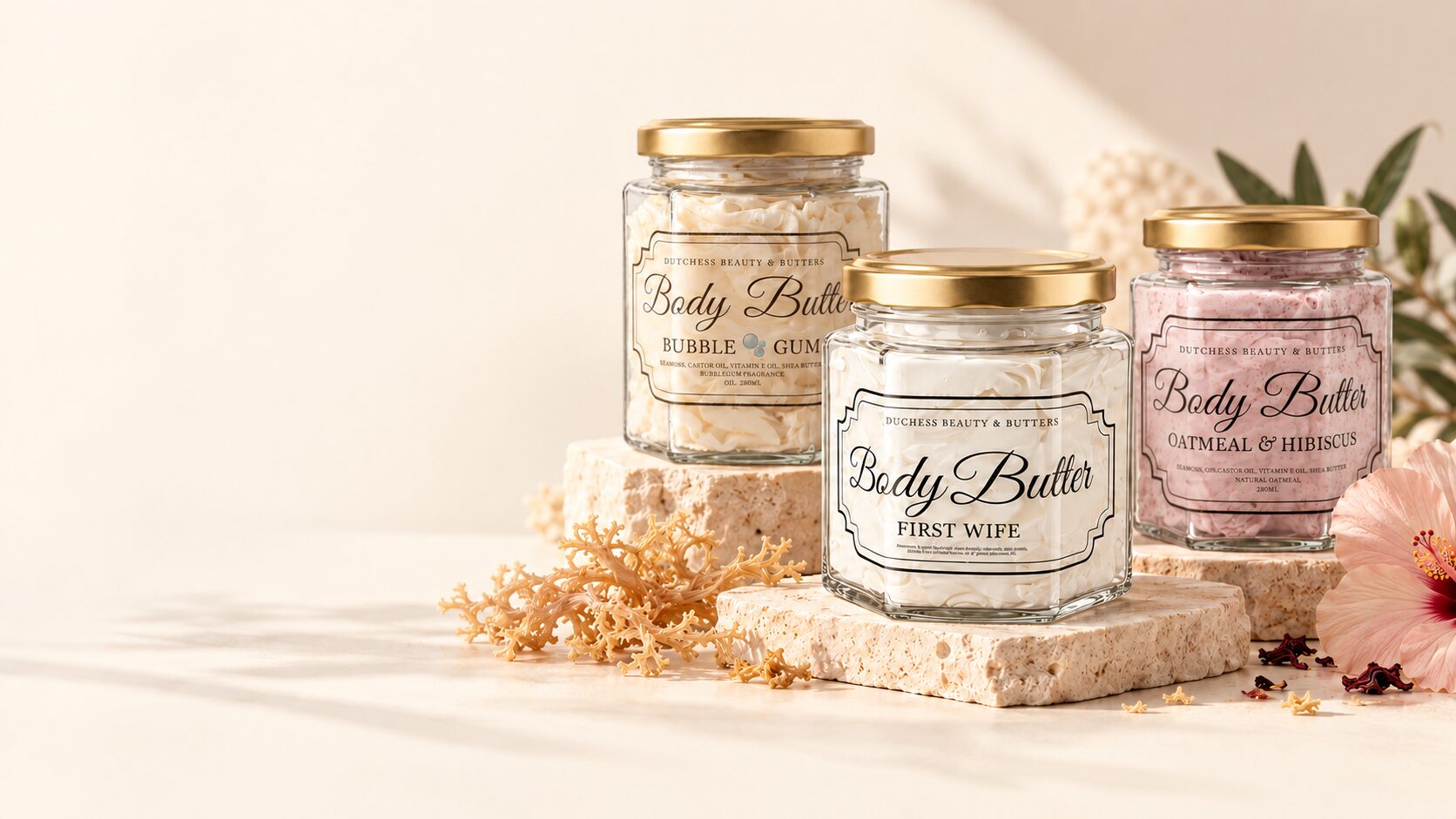 Dutchess body butter jars in Bubble Gum, First Wife and Oatmeal & Hibiscus on travertine stones with seamoss and hibiscus