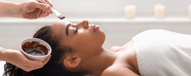 A client relaxing during a facial as a mask is brushed on